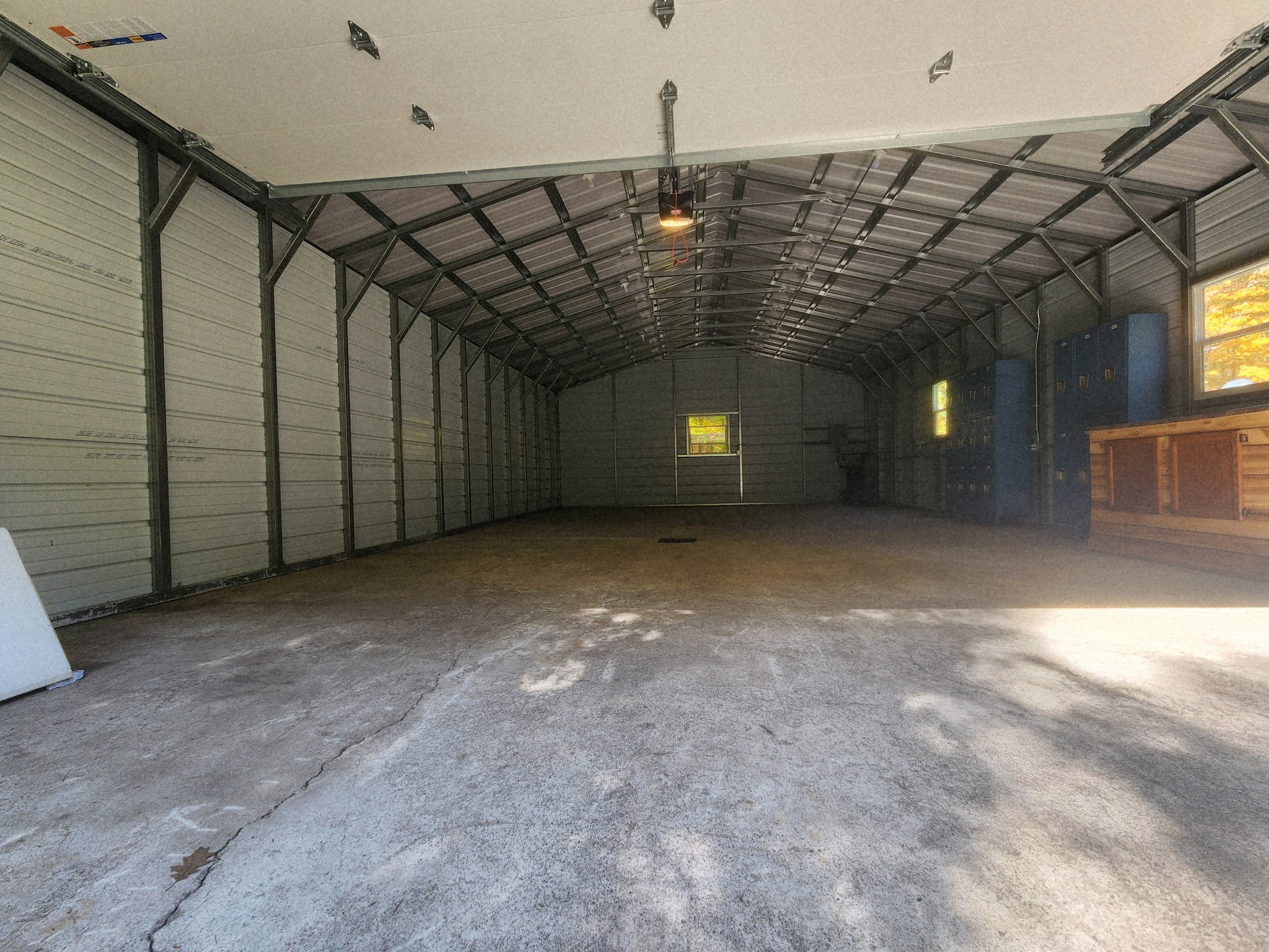 The same steel outbuilding after the cleanout, emptied to a clear concrete floor with the blue lockers along the wall.