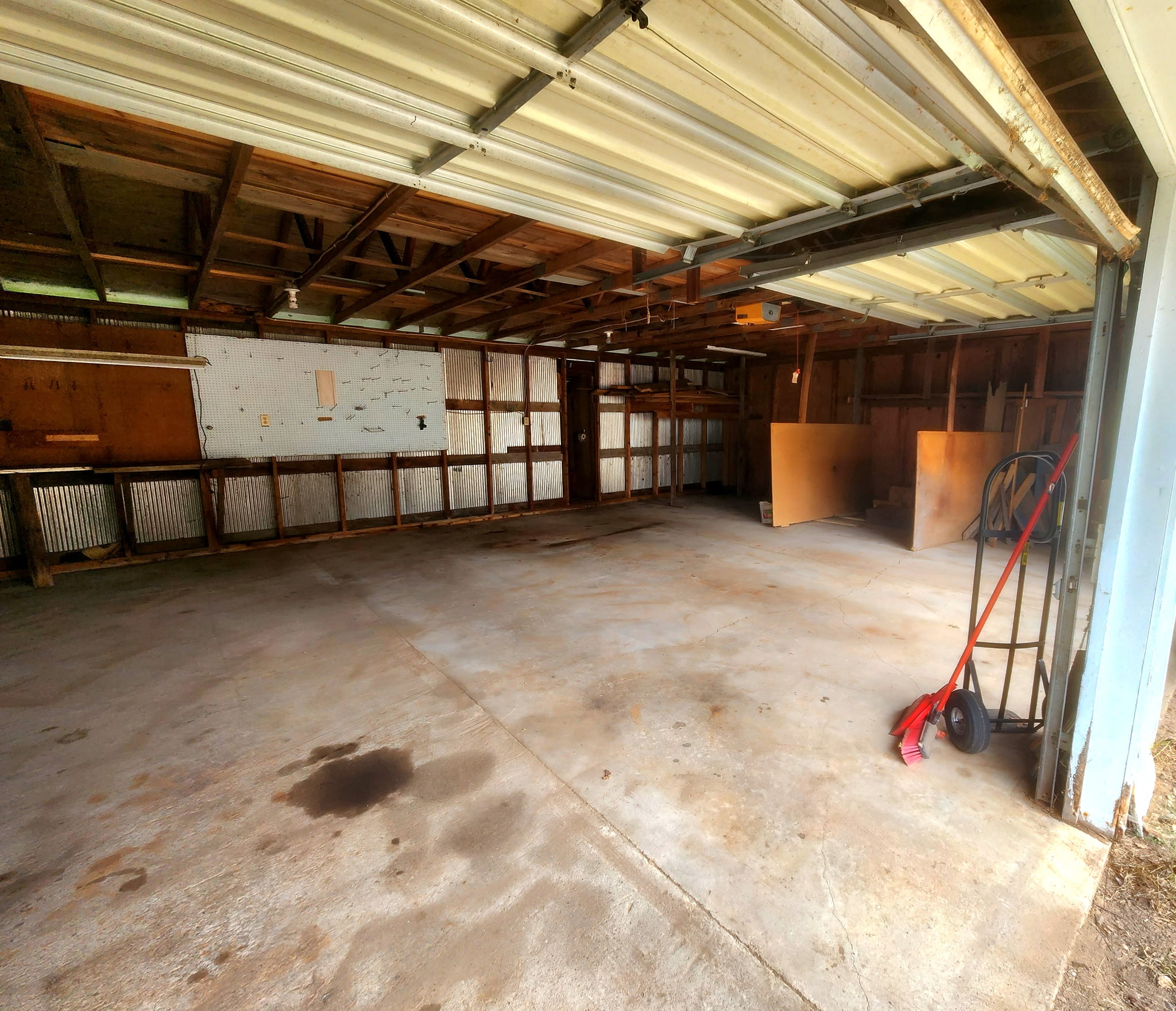 The same garage after the cleanout, swept and cleared down to the bare concrete floor and empty pegboard walls.
